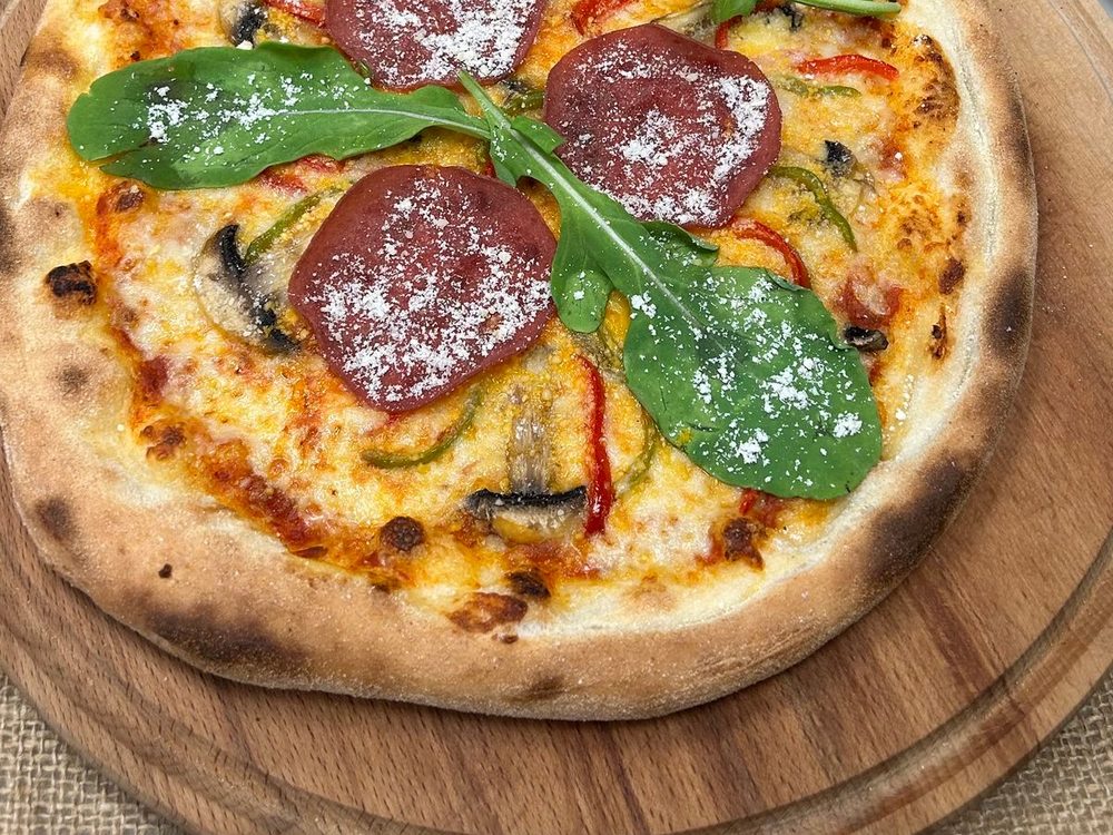 Gourmet pizza with cured salami, rocket and shaved parmesan